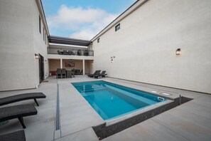 Piscina com espreguiçadeiras e área de estar coberta.