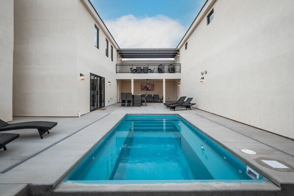 A swimming pool with lounge chairs and a dining area in a courtyard. - Spacious Brand New Home! Lots of courtyard space and fun for all. (Hurricane)