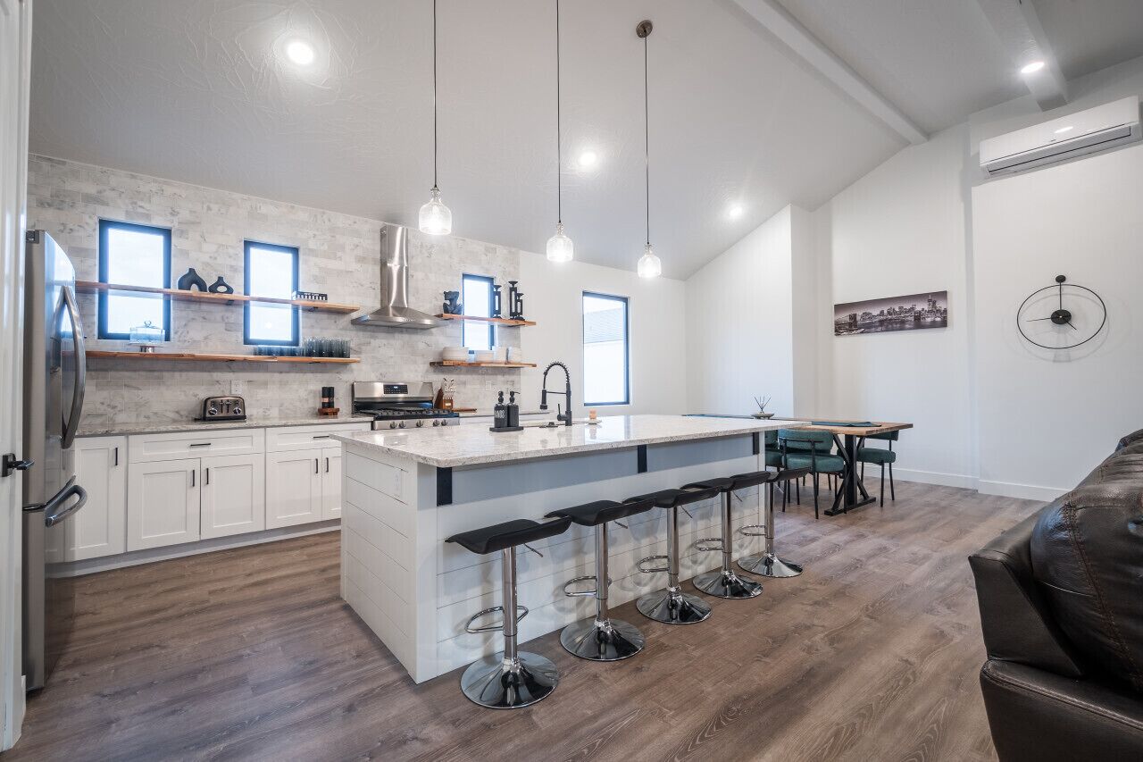 A modern kitchen with a central island, bar stools, and pendant lighting.