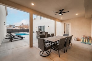 A covered patio area with a pool, dining table, and chairs. - Spacious Brand New Home! Lots of courtyard space and fun for all. (Hurricane)