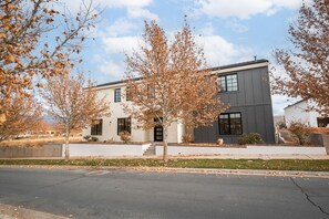 A modern two-story building with a flat roof, large windows, and a visible entrance. - Spacious Brand New Home! Lots of courtyard space and fun for all. (Hurricane)