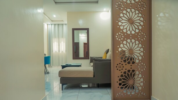 Una sala de estar moderna con un sofá, una mesa de centro y un panel decorativo con diseños intrincados.