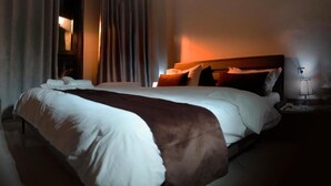 Una habitación de hotel con una cama grande, una mesita de noche con lámpara y un aparador.