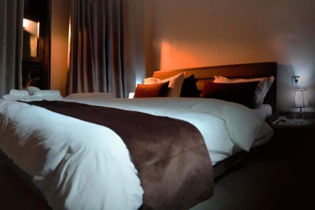 Una habitación de hotel con una cama grande, una mesita de noche con lámpara y un aparador.