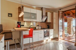 A modern kitchen with white cabinets, a built-in oven, and a red chair.