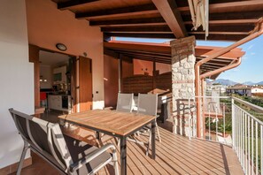 An outdoor dining area with a wooden table and chairs, a stone pillar, and a view of the mountains.