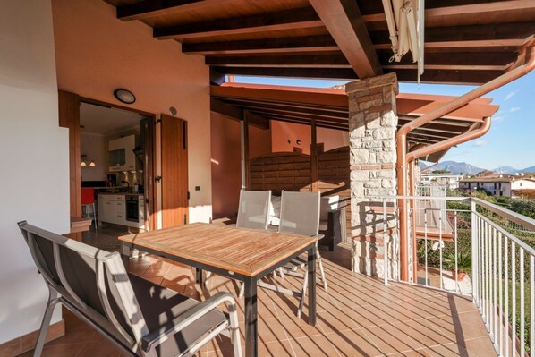 Un espacio exterior para comer con mesa y sillas de madera, un pilar de piedra y vistas a la montaña.