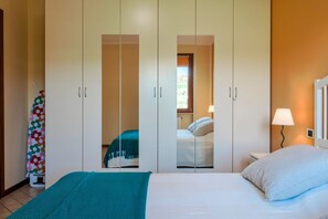 A bedroom with a bed, a nightstand, a lamp, and a wardrobe with a mirror. - I BROLI - lovely nest with pool (Rio Marle)