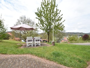 A patio with two white chairs and a table, a picnic table with a canopy, and a lamppost. - Peaceful Getaway in Nature (VARSBERG)