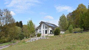 Et moderne hus med skråt tag, solpaneler og en indhegnet have.