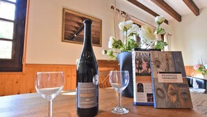 A bottle of Domaine de la Ramelette Bourgogne wine, two wine glasses, and a book titled 'Frankrijk Voorgood' on a wooden table in a room with wooden walls and a window. - Holiday Home in Le Châtelet with Pool (Le Châtelet)
