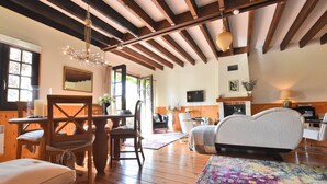 A cozy room with wooden floors, a dining table, chairs, a sofa, a TV, and a fireplace. - Holiday Home in Le Châtelet with Pool (Le Châtelet)