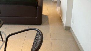 Ein modernes Hotelzimmer mit einem wandmontierten Flachbildfernseher, einem Sofa, einem Sessel und einer eingebauten Garderobe mit Regalen.