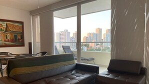 Ein modernes Wohnzimmer mit einer Ledersofa, einem Esstisch mit Stühlen und einem großen Fenster mit Blick auf die Stadt.
