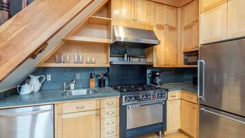 Una cocina compacta con armarios de madera, un refrigerador de acero inoxidable, una estufa a gas y un horno empotrado.