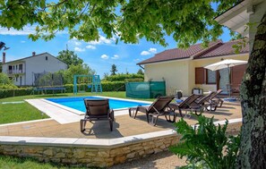 Ein Garten mit Pool, Liegestühlen, einer Schaukel und einer Steinmauer.
