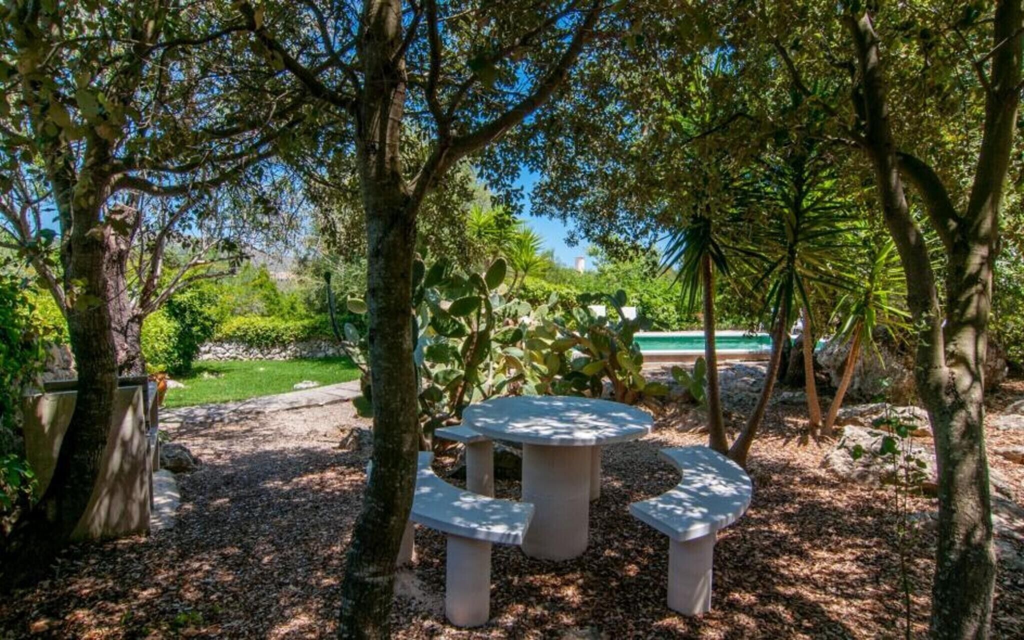 A garden with a stone table and benches surrounded by trees and plants.