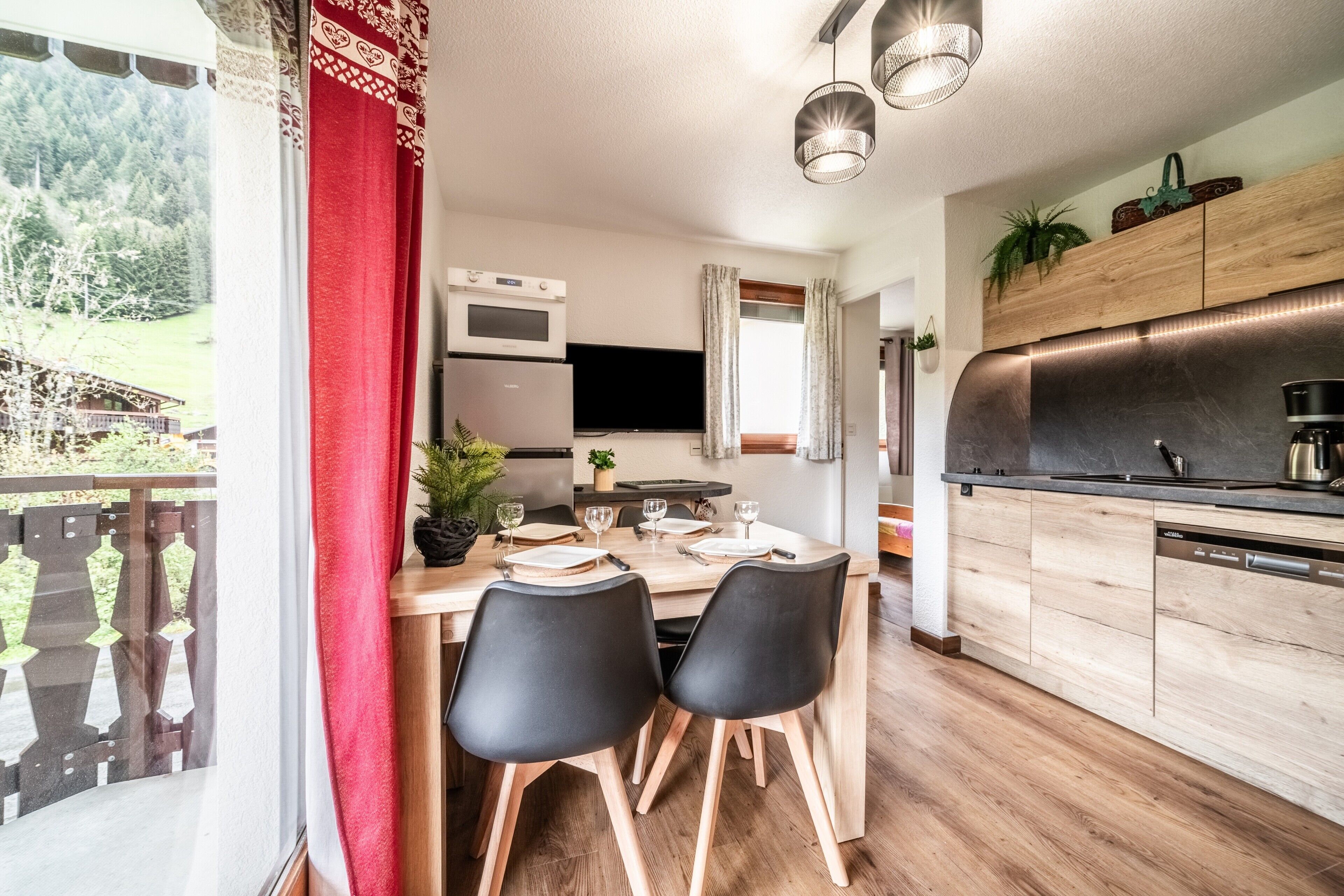 A modern kitchen with wooden cabinets, a built-in oven, and a large window overlooking a scenic outdoor area.