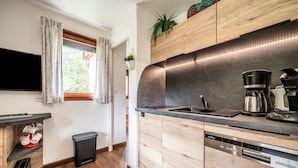 A modern kitchen with wooden cabinets, a built-in dishwasher, and a coffee maker. - Apartment 'Les Avenières' with Balcony (Châtel)