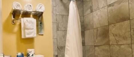 A bathroom with a toilet, a bathtub with a shower curtain, and a towel rack with towels.