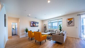 A modern living room with hardwood flooring, a gray sofa, yellow chairs, and a coffee table.