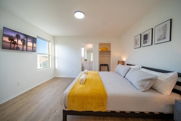 A bedroom with a bed, a window, and a door leading to a bathroom.