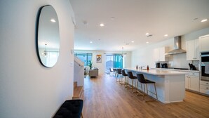 A modern kitchen with a central island, bar stools, and a large mirror.