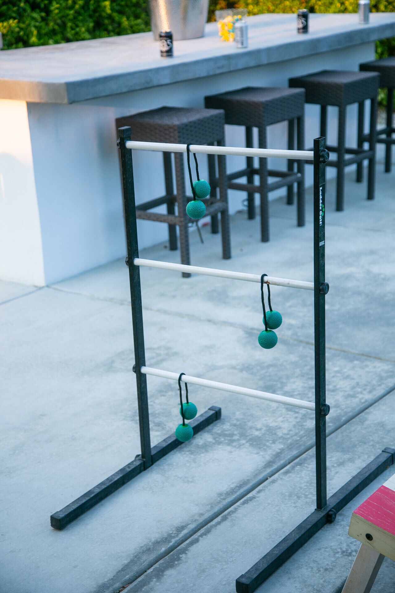 A metal rack with teal spherical weights, a concrete floor, and a bar area with stools and a counter in the background.