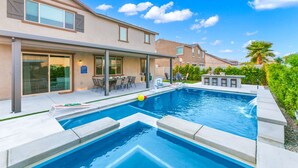 A modern house with a swimming pool, patio with outdoor furniture, and a well-maintained garden.