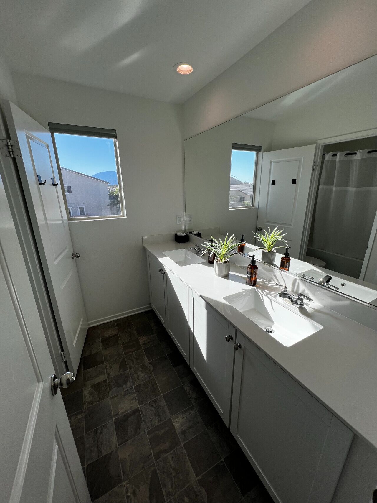 Un baño moderno con dos lavamanos, un espejo grande y una ventana.