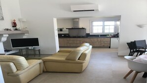 A modern living room with a beige sectional sofa, a flat-screen TV, and a dining area with a table and chairs. - Holiday Home Provence with Pool (Céreste)