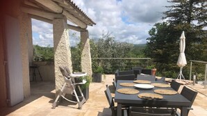 An outdoor patio with a table and chairs, a baby stroller, and a pergola structure. - Holiday Home Provence with Pool (Céreste)