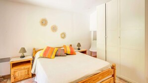 Un dormitorio con cama de madera, paredes blancas y un armario.
