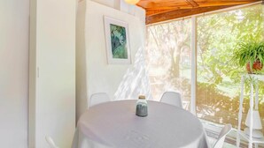 Una mesa redonda con mantel blanco, una lámpara colgante y un cuadro en la pared.
