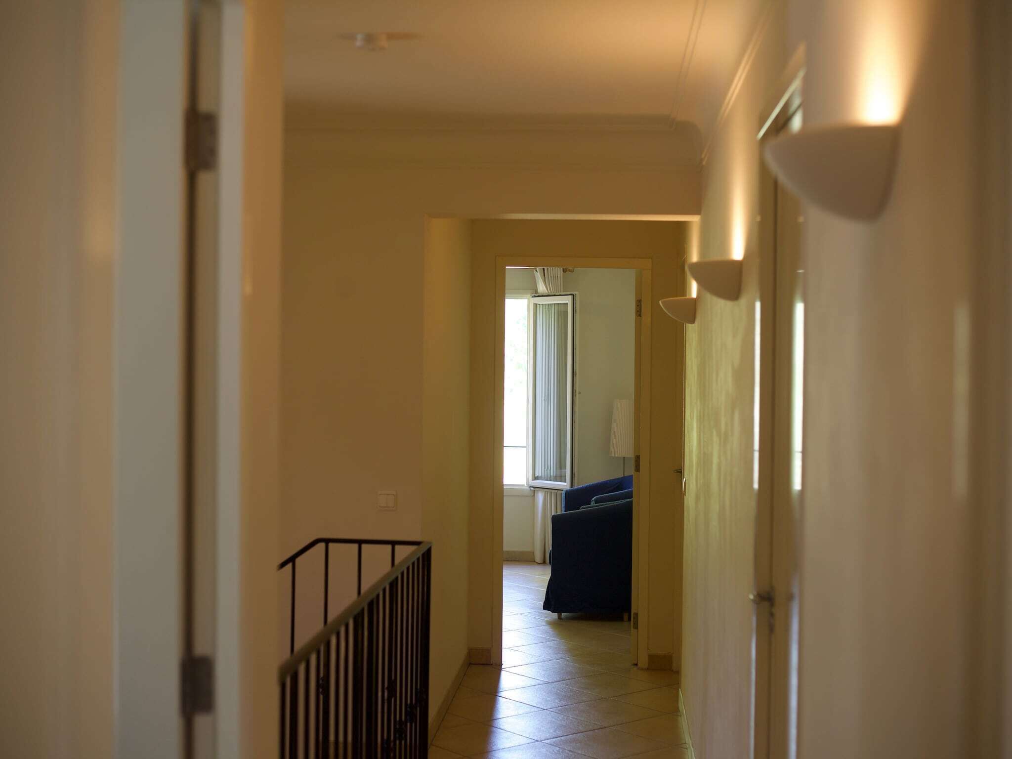 En hall med en trappa som leder upp till ett rum med en säng och ett fönster.