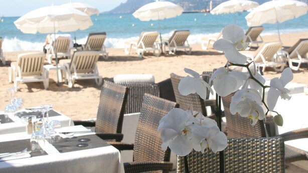 A beachside restaurant with outdoor seating, white umbrellas, and white chairs. - Elegant Villa with Pool, Cabris (Cabris)