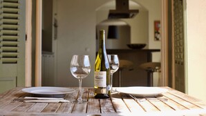 A wooden table with a bottle of wine, two glasses, and a plate, set in a doorway leading to a kitchen area. - Elegant Villa with Pool, Cabris (Cabris)
