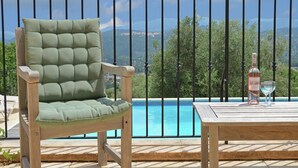 A wooden chair with a cushioned backrest and a table with a bottle and glasses, overlooking a swimming pool and a mountainous landscape. - Elegant Villa with Pool, Cabris (Cabris)
