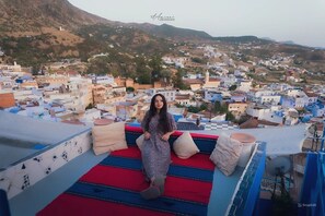 A person sitting on a rooftop terrace with a cityscape view. - Dar Dauia  (Chefchaouen)