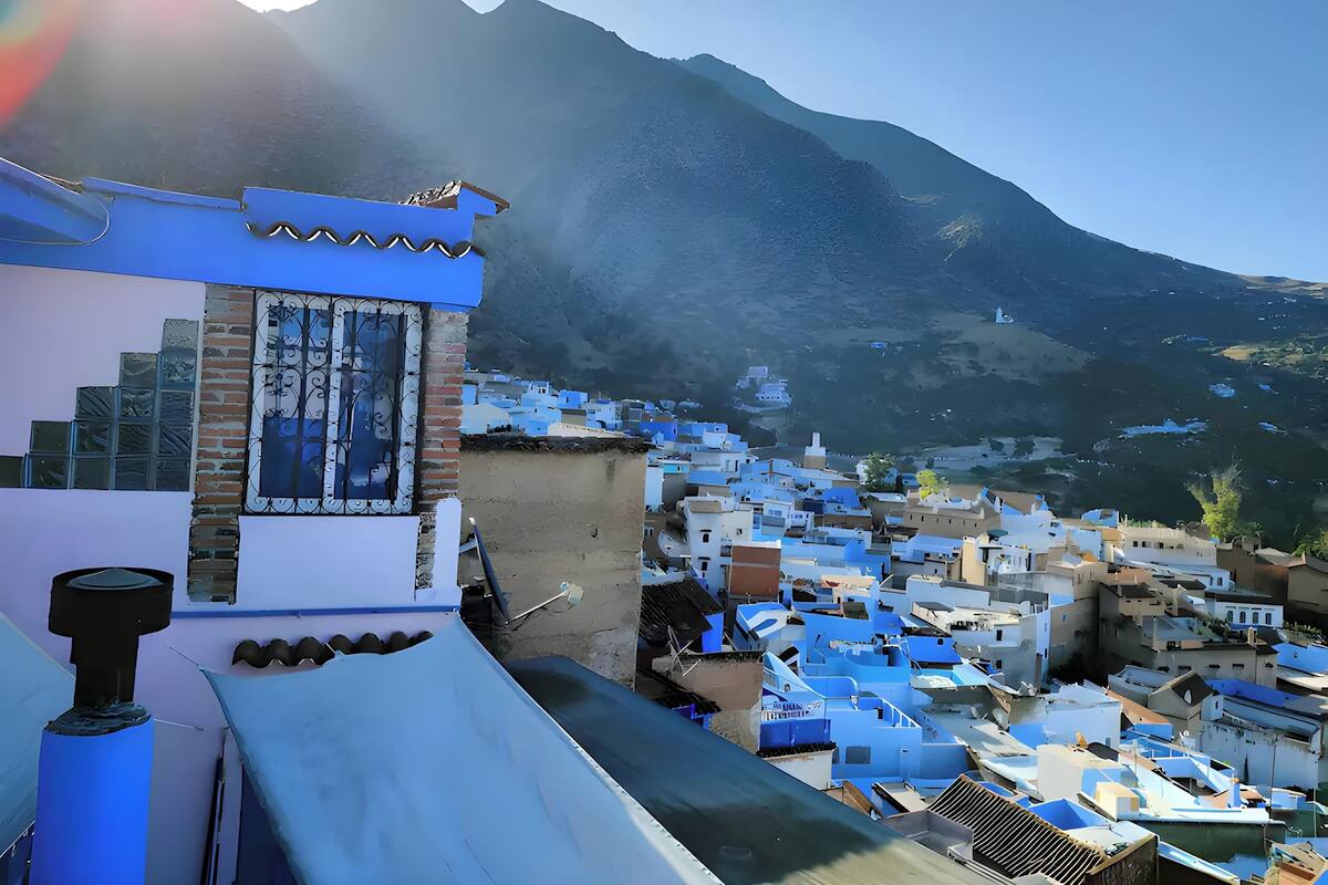 Paisagem montanhosa com uma aldeia de edifícios com telhados azuis.