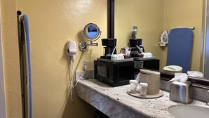 A bathroom with a sink, mirror, hair dryer, coffee maker, and various toiletries. - Cozy Standard Queen Room Near Beach and Across Lake! (Monterey)