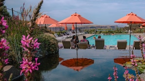 A poolside area with lounge chairs and orange umbrellas, surrounded by natural vegetation and a clear view of the landscape. - Sagecliffe Resort & Spa (Quincy)
