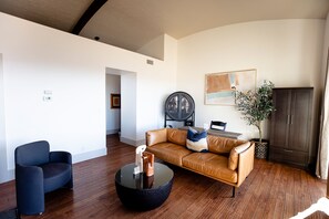 A modern living room with a leather sofa, a round coffee table, and a dark armchair.