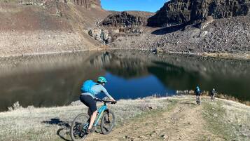 A mountain biking trail with a lake and rocky cliffs in the background.