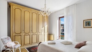 Une chambre à coucher avec un lit, une chaise, une armoire et un lustre.