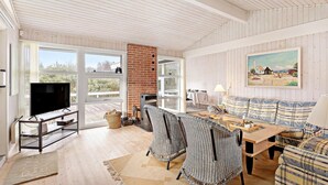 A spacious living room with a large TV, wicker furniture, a fireplace, and a painting on the wall.