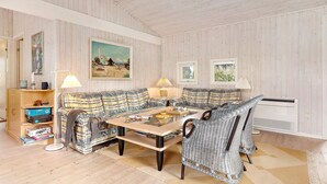 A cozy living room with a plaid sofa, a wooden coffee table, and a bookshelf.