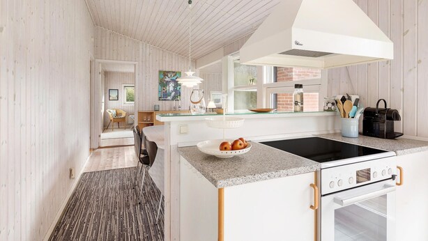A modern kitchen with a central island, a built-in oven, and a hanging light fixture.