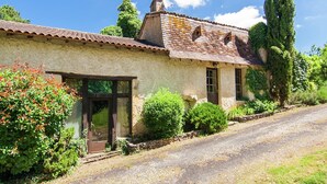 A rustic stone building with a tiled roof, a wooden door, and a gravel driveway. - Mansion  in Bourgnac with garden (Bourgnac)