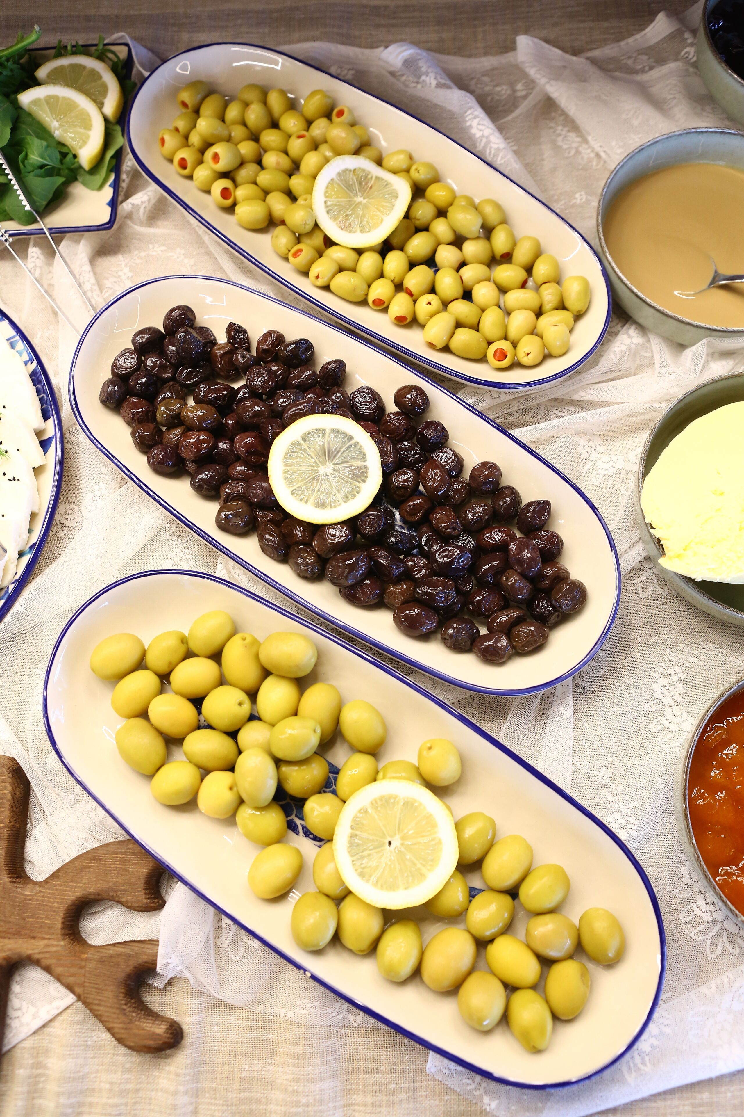 A table with various dishes including olives and lemon slices.